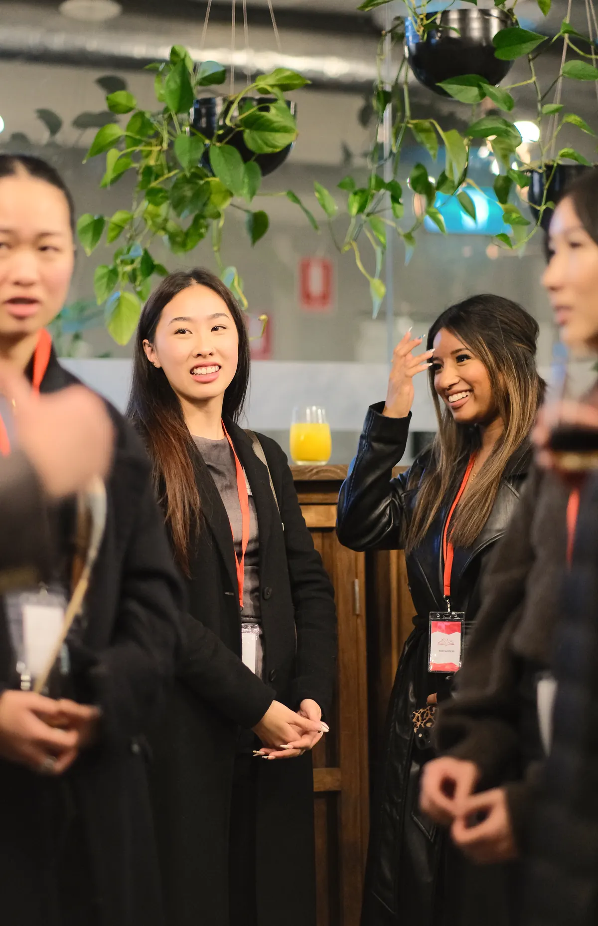 Two members talking and laughing at a BNB Success event, drinks in hand.