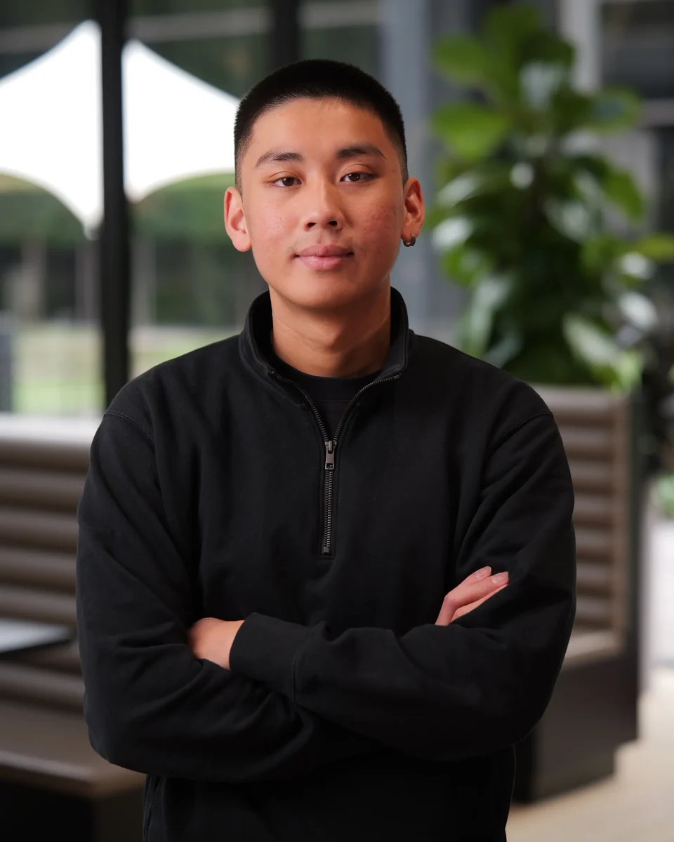 Jordan Pham, co-founder of BNB Success, in a black quarter-zip with his arms crossed.
